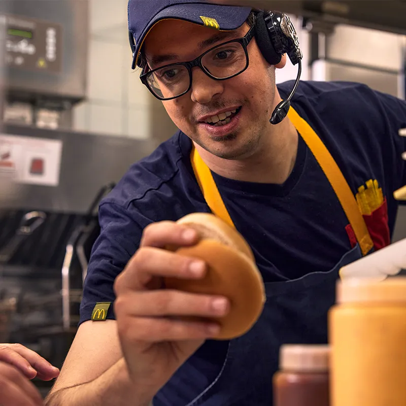 McDonald’s Mitarbeiter mit Headset bei der Burger-Zubereitung